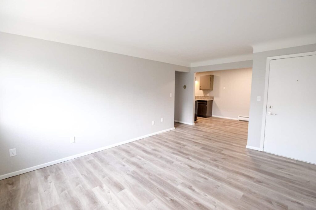 Large living room space with a nice flow into the kitchen and dining area, featuring wood flooring.